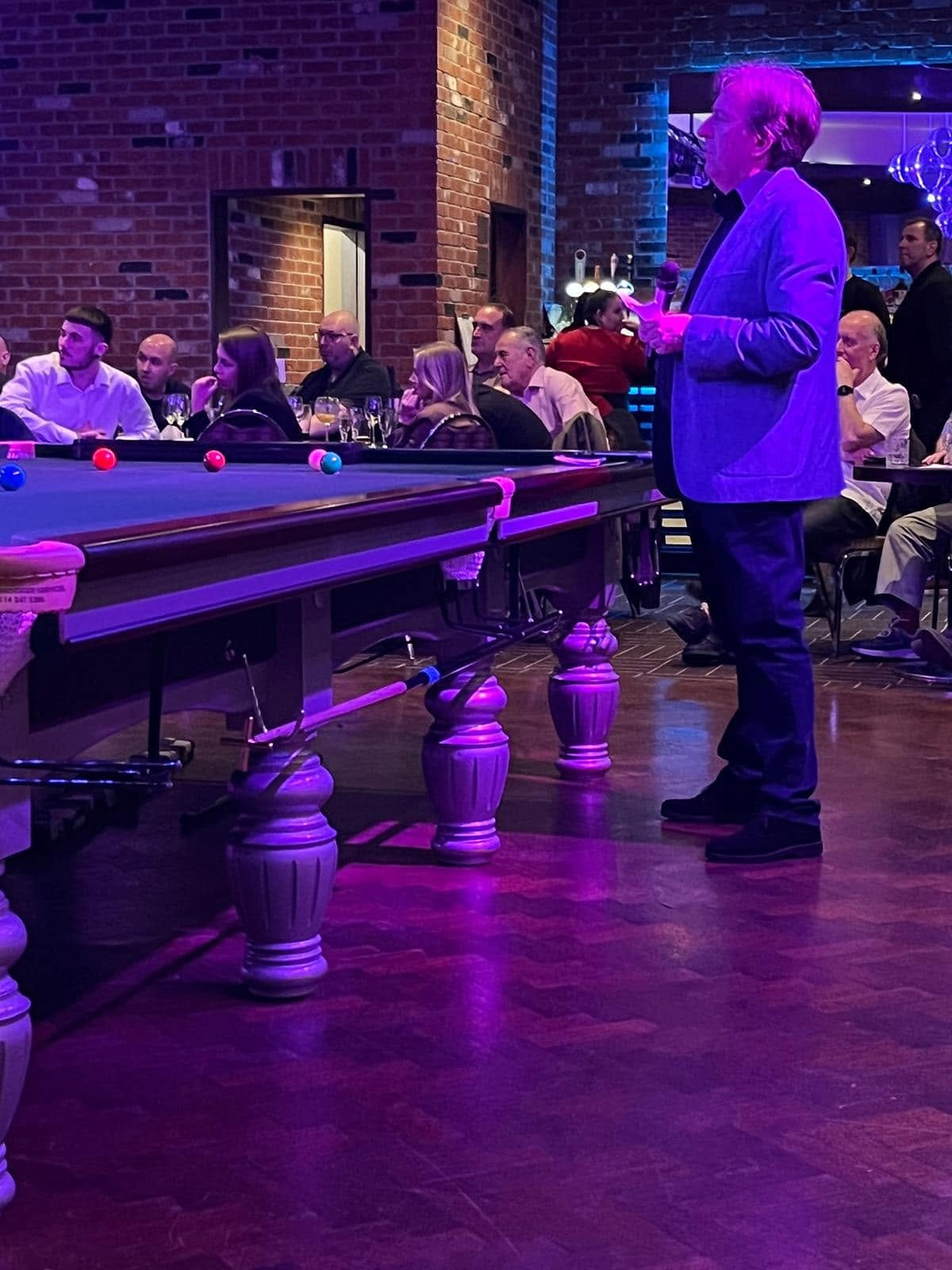 Nick Johnson compering an evening event beside a snooker table